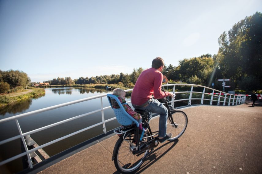 A cyclist (with child) on a bridge over the river Rotte