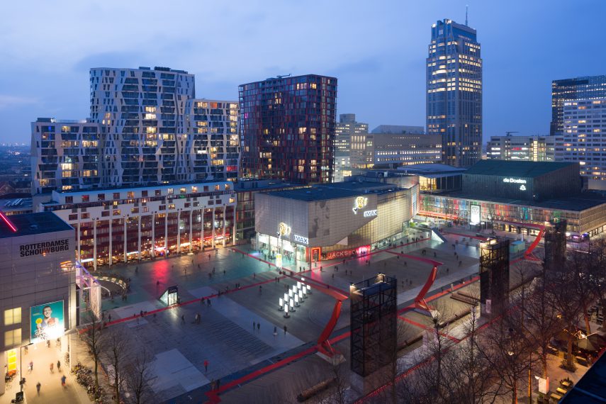 View of the Schouwburgplein, designed by Adriaan Geuze. The broken red light poles refer to harbor cranes. Left on the square is the Rotterdamse Schouwburg, center back shows the Calypso, and right the Millenniumtoren.