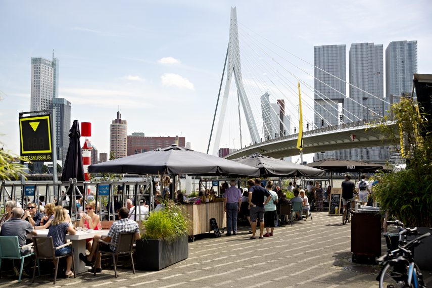 People at the Prachtig terrace, close to Erasmusbridge. De Rotterdam (building) visible in the background.