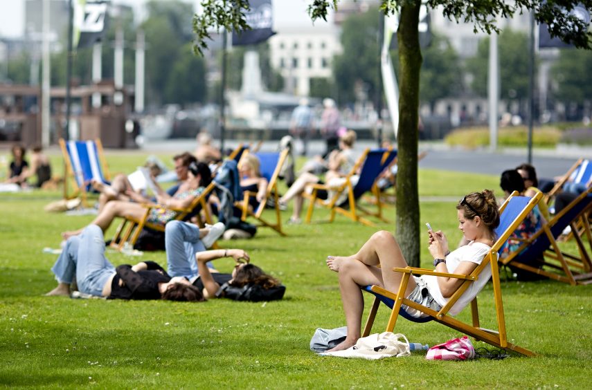 People sitting on a lawn and in deck chairs