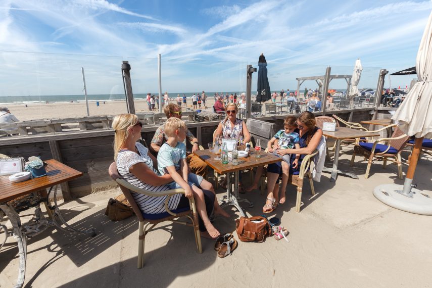 Hoek van Holland: Mensen met kinderen op terras aan strand Hoek van Holland.