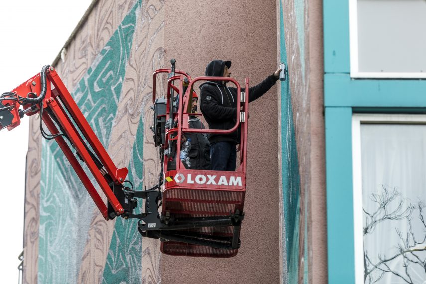 Kunstenaar Astro werkt aan zijn nieuwe street art kunstwerk op de gevel van restaurant Ayla.