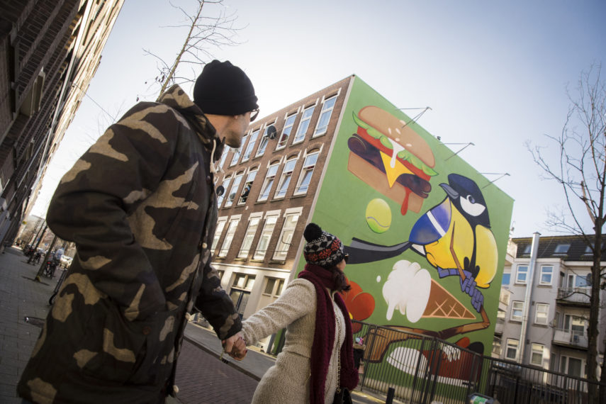 Stel loopt langs het kunstwerk van artist Ready2Rumbl.  Locatie: Van Speykstraat. 