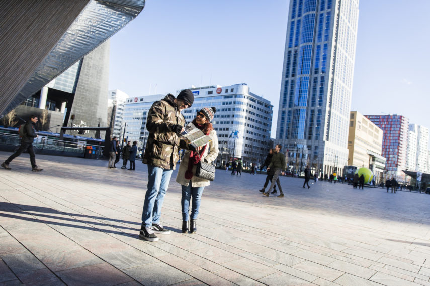 Couple looks at the map of Rotterdam on the station square.