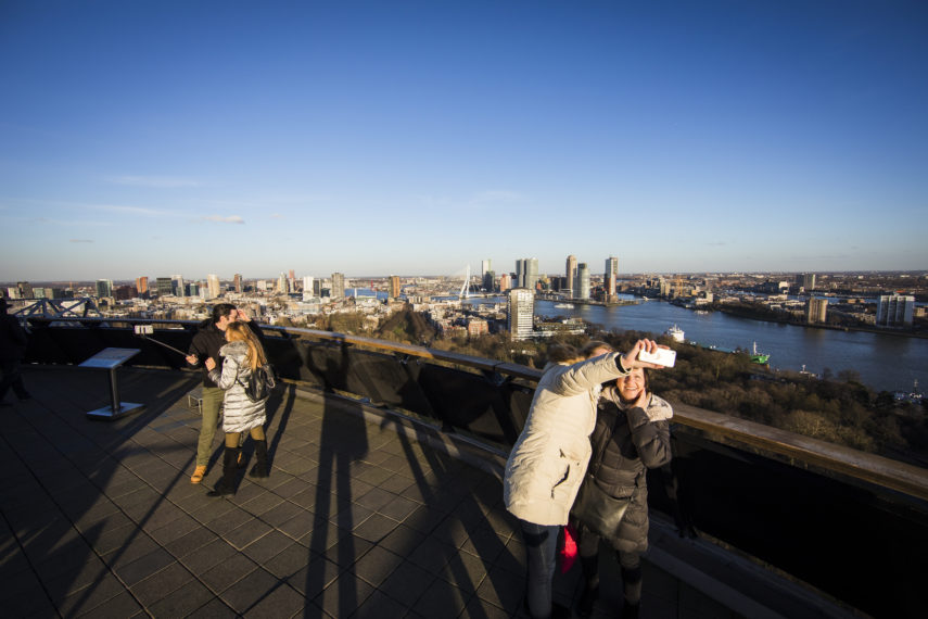 Visitors take a selfie on the Euromast with the skyline of Rotterdam in the background.