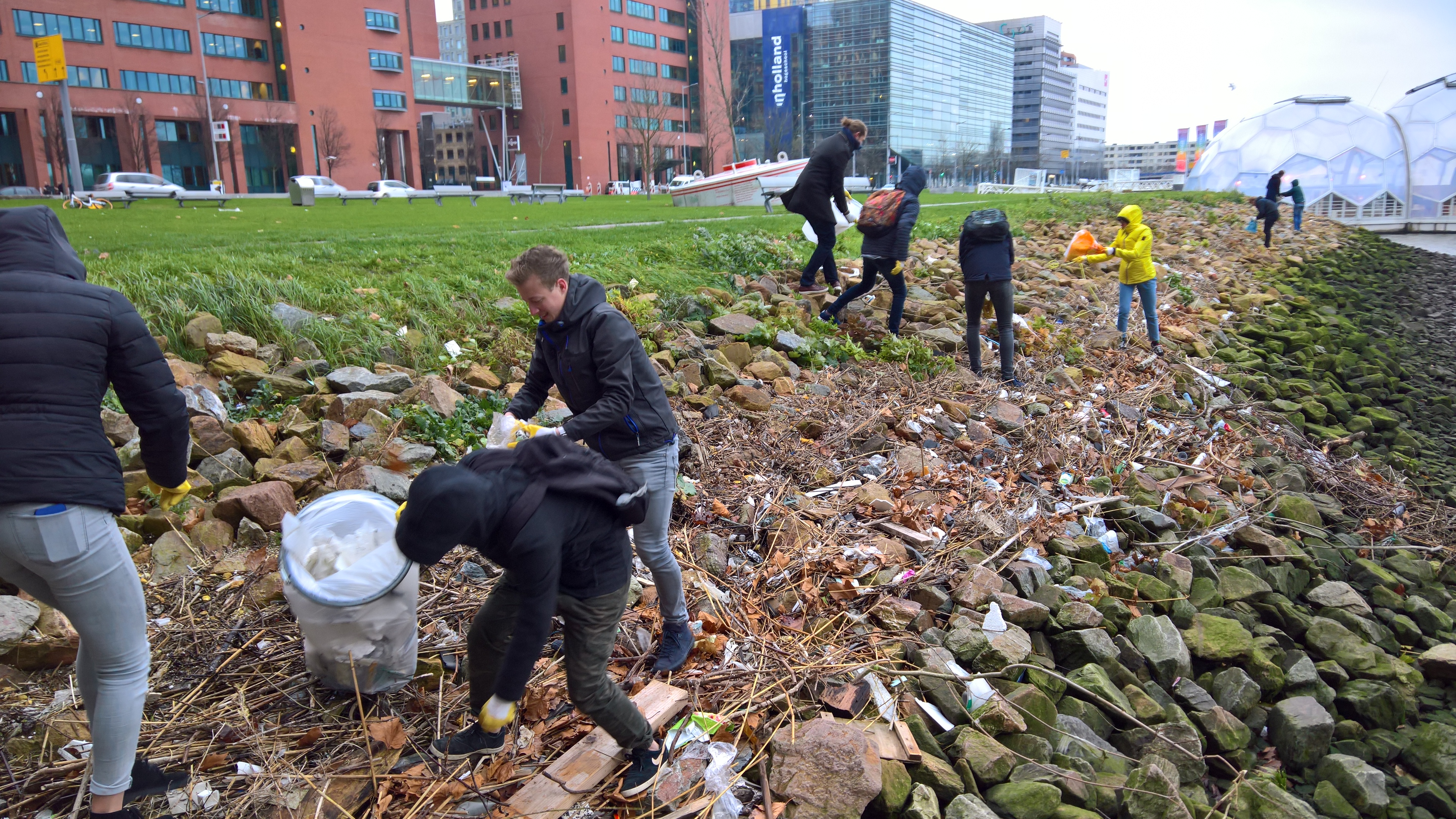 Volunteers collecting plastic waste materials from a river bank