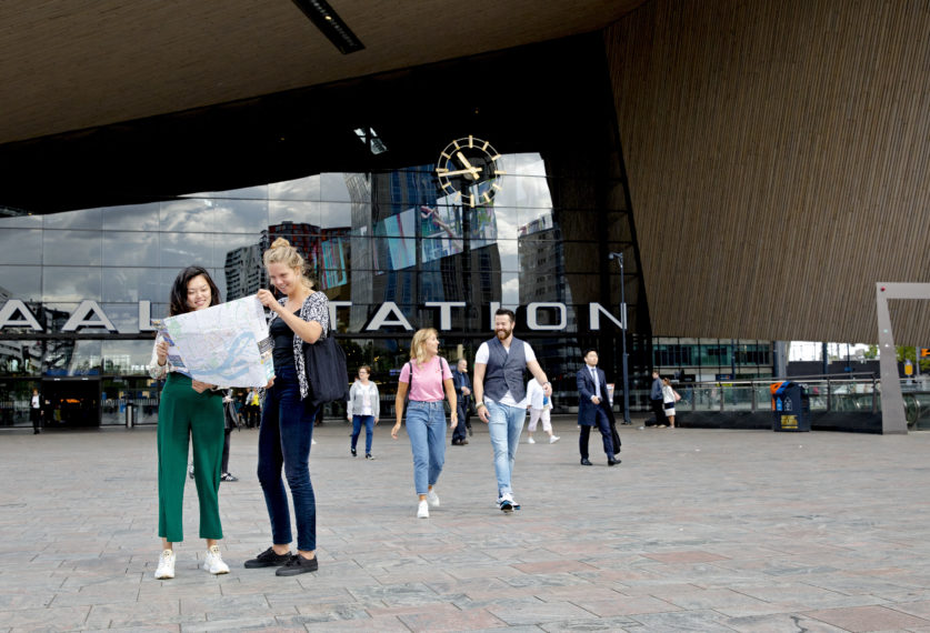 Toeristen bekijken de kaart van Rotterdam op het Stationsplein.