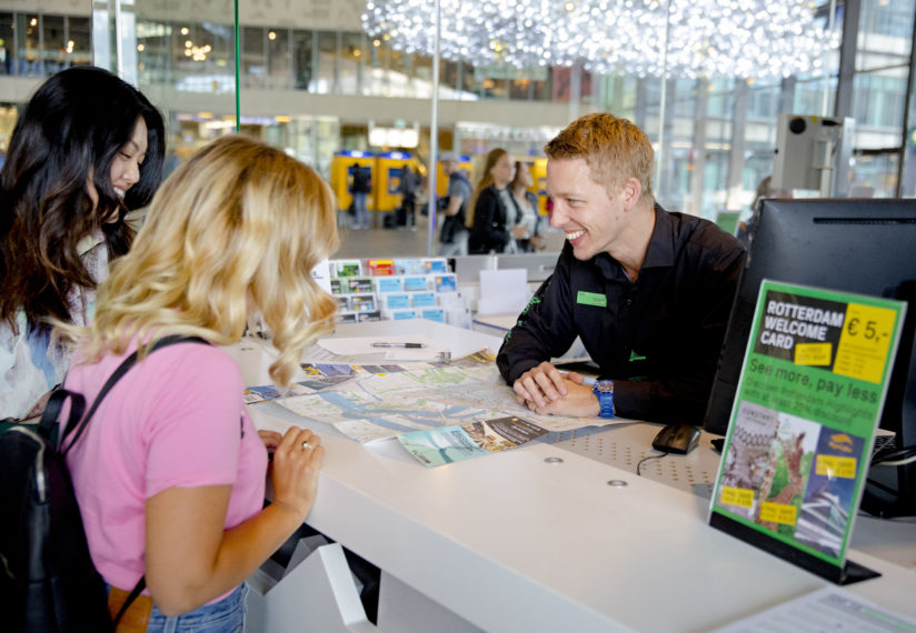 Toeristen worden geholpen aan de balie van de Rotterdam Tourist Information.
