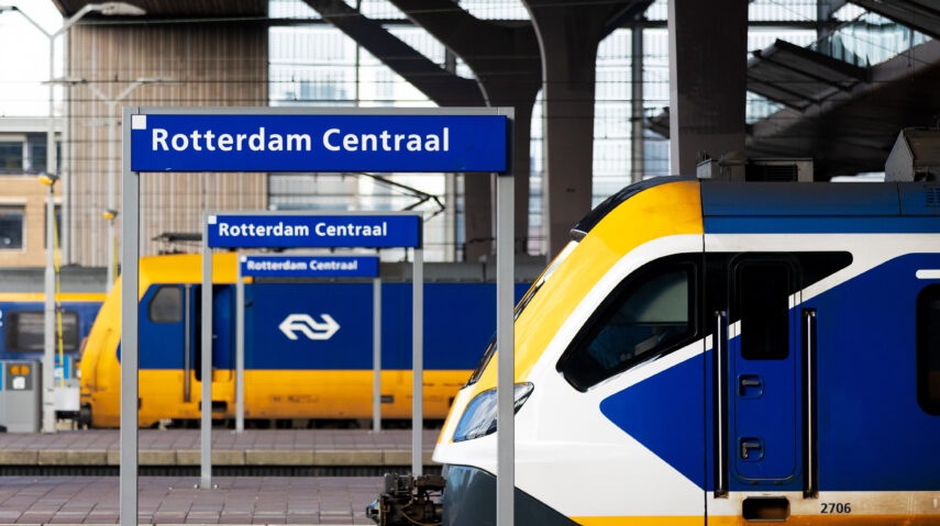 Een foto van het centraal station van Rotterdam waarop enkele passerende of stoppende treinen zijn vastgelegd. Station Rotterdam Centraal wordt ook wel de internationale toegangspoort tot Rotterdam genoemd. Dagelijks passeren zo