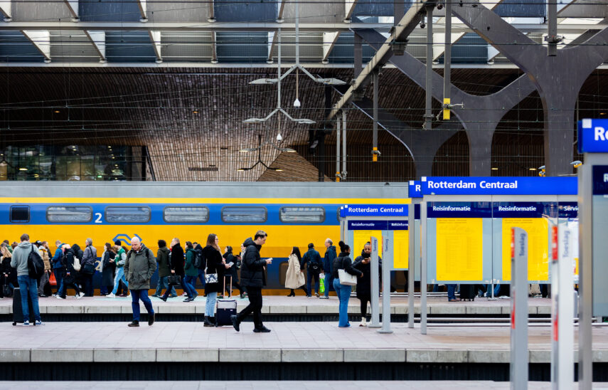 Rotterdam Centraal Station vastgelegd op een druk moment, met een menigte die over het perron beweegt, met een trein op de achtergrond. Station Rotterdam Centraal wordt ook wel de internationale toegangspoort tot Rotterdam genoemd. Dagelijks passeren zo