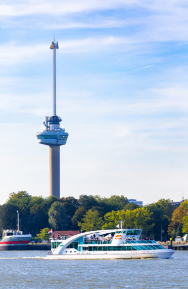 Een foto van de iconische uitkijktoren Euromast en een Spido-boot op de Maas.
