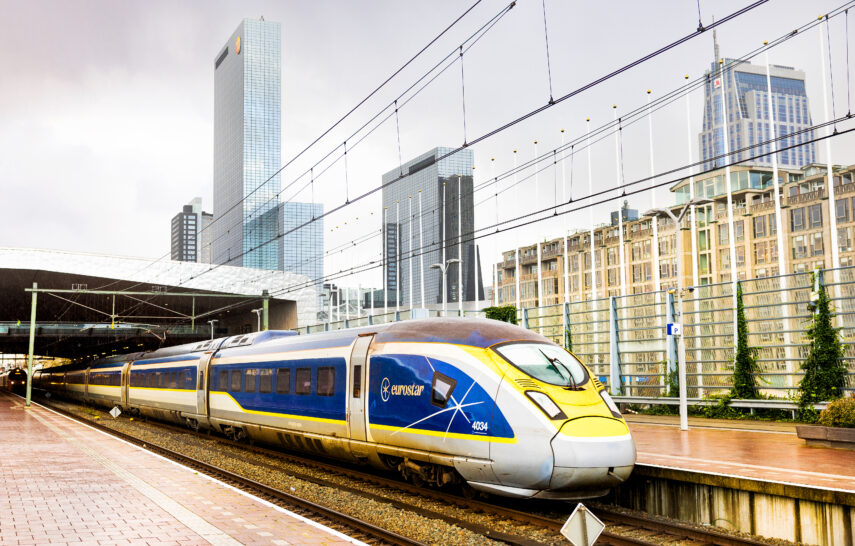 A Eurostar train departs from Rotterdam Central Station. Part of the skyline is visible in the background, with the Delftse Poort highrise.