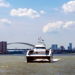 Waterbus op de Maas met de Van Brienenoord brug en de stad op de achtergrond. Foto: Worcflow