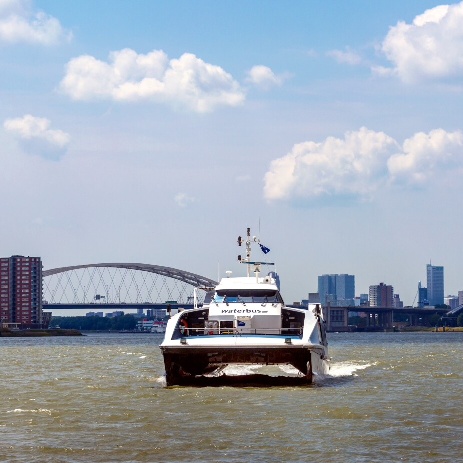 Waterbus op de Maas met de Van Brienenoord brug en de stad op de achtergrond. Foto: Worcflow