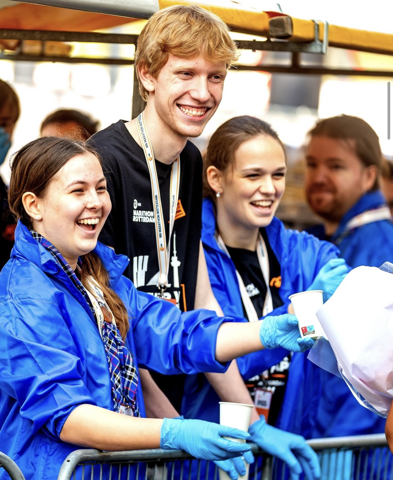 Groep jonge vrijwilligers deelt drinken uit bij een evenement.