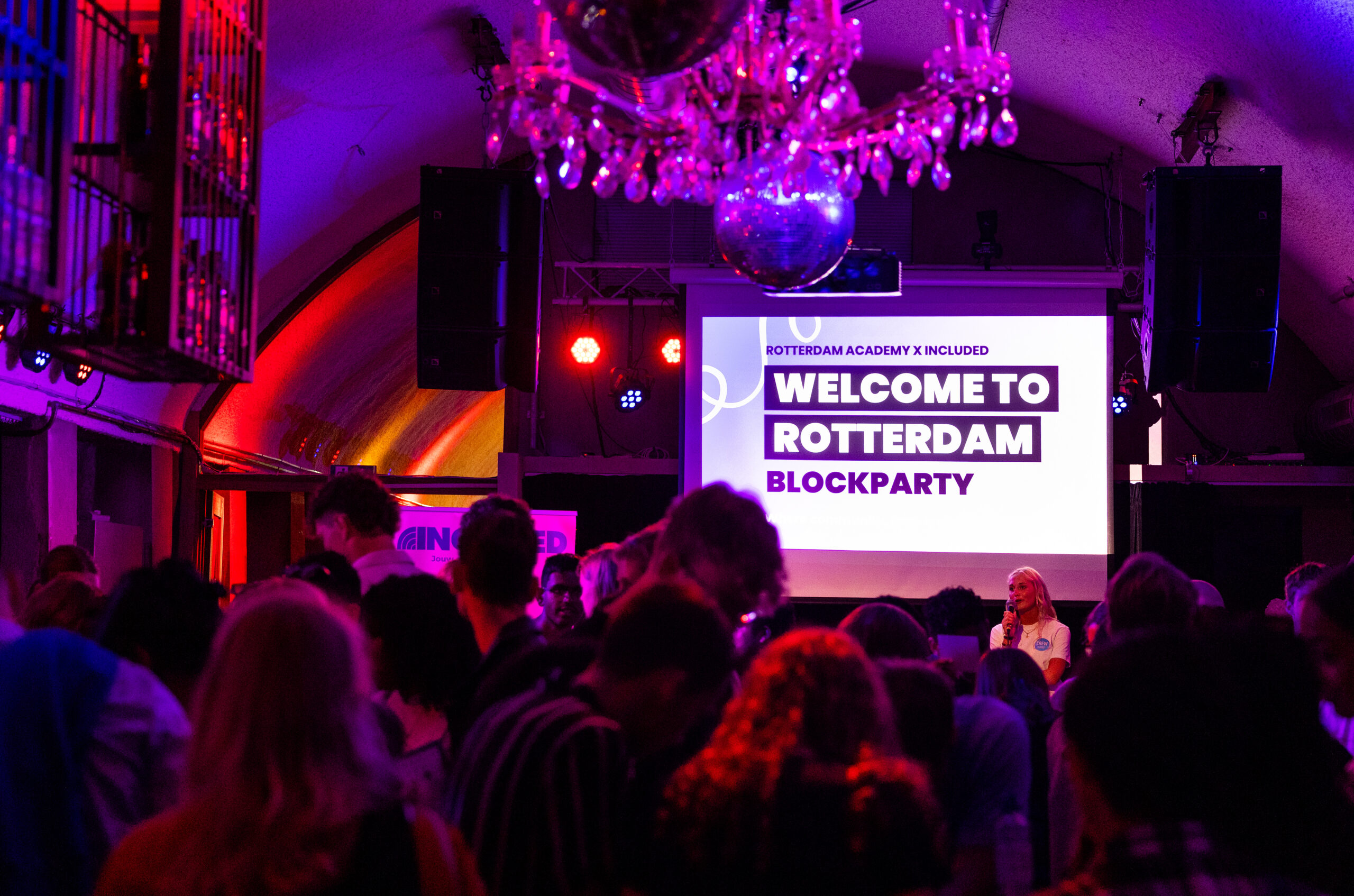 Feestelijke bijeenkomst met mensen en een scherm met de tekst 
