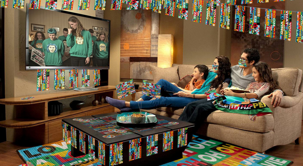 Gezin kijkt televisie in kleurrijk versierde woonkamer met feestelijke banners.