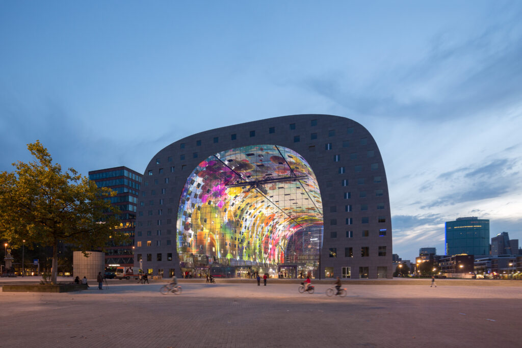Overzicht van het interieur van de Markthal. De koepel is versierd met afbeeldingen van de verse producten die verkocht worden in de hal. Het ontwerp van dit kunstwerk is van Arno Coenen en Iris Roskam.