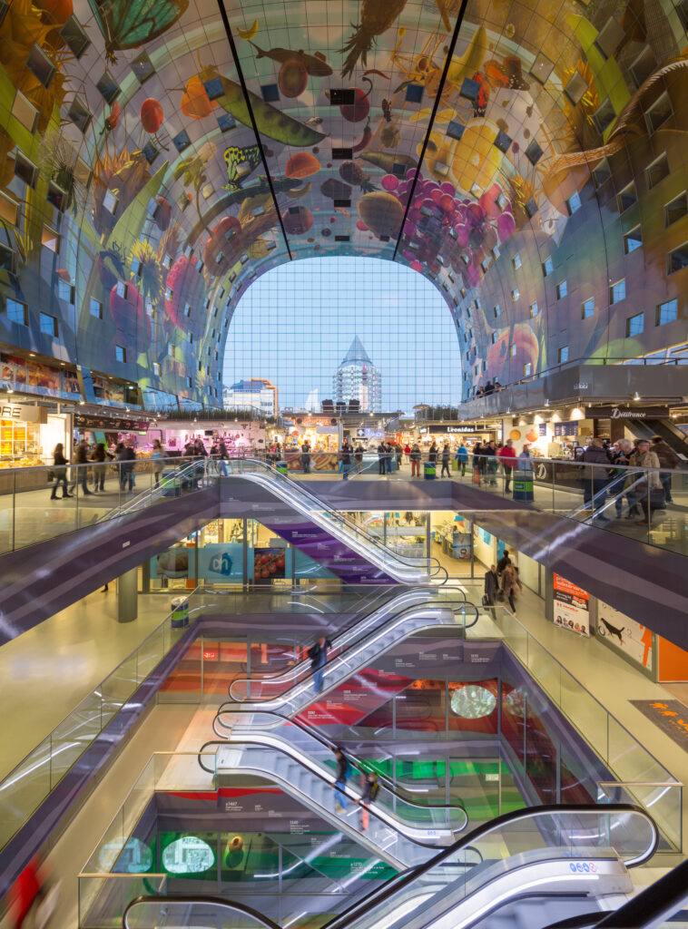 Overzicht van het interieur van de Markthal. De koepel is versierd met afbeeldingen van de verse producten die verkocht worden in de hal. Het ontwerp van dit kunstwerk is van Arno Coenen en Iris Roskam.