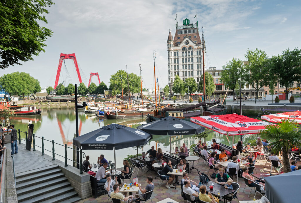 Terras aan de Oude Haven, de oudste haven in het centrum van Rotterdam. Nu is het vooral een uitgaansgebied. Op de achtergrond Het Witte Huis, bij zijn oplevering in 1898 het hoogste kantoorgebouw van Europa. Linksachter de rode Willemsbrug.