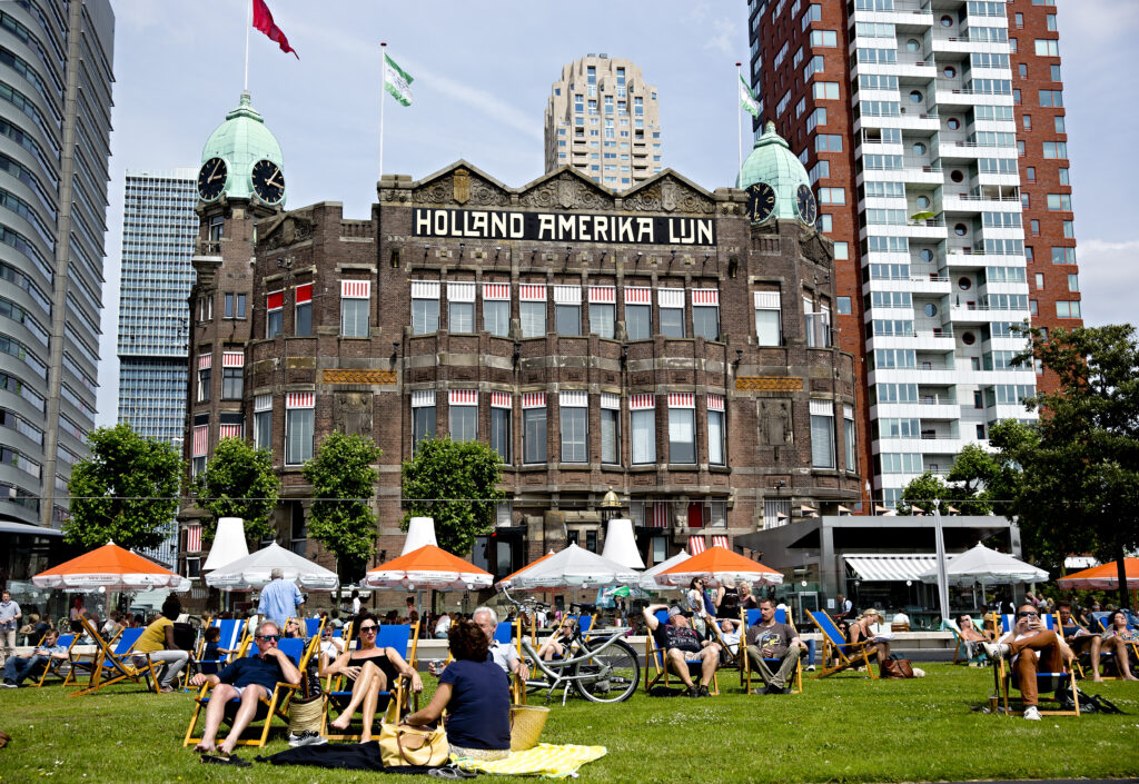 Mensen genieten van de zon op het grasveld voor Hotel New York.