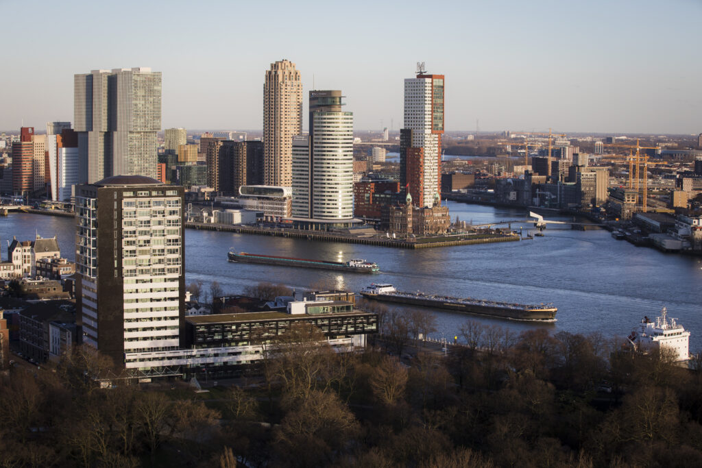 Schepen varen bij Kop van Zuid langs De Rotterdam en Hotel New York.