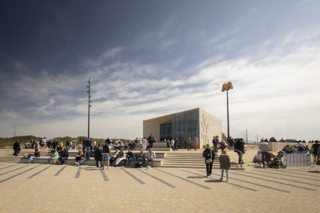 Toeristen genieten van de zon en van het uitzicht bij metrohalte Hoek van Holland Strand. Sinds 31 maart 2023 stopt metrolijn B op (eind)halte Hoek van Holland Strand. Hiermee reis je in 37 minuten tussen Rotterdam centrum en het strand, ook wel Rotterdam Beach genoemd.