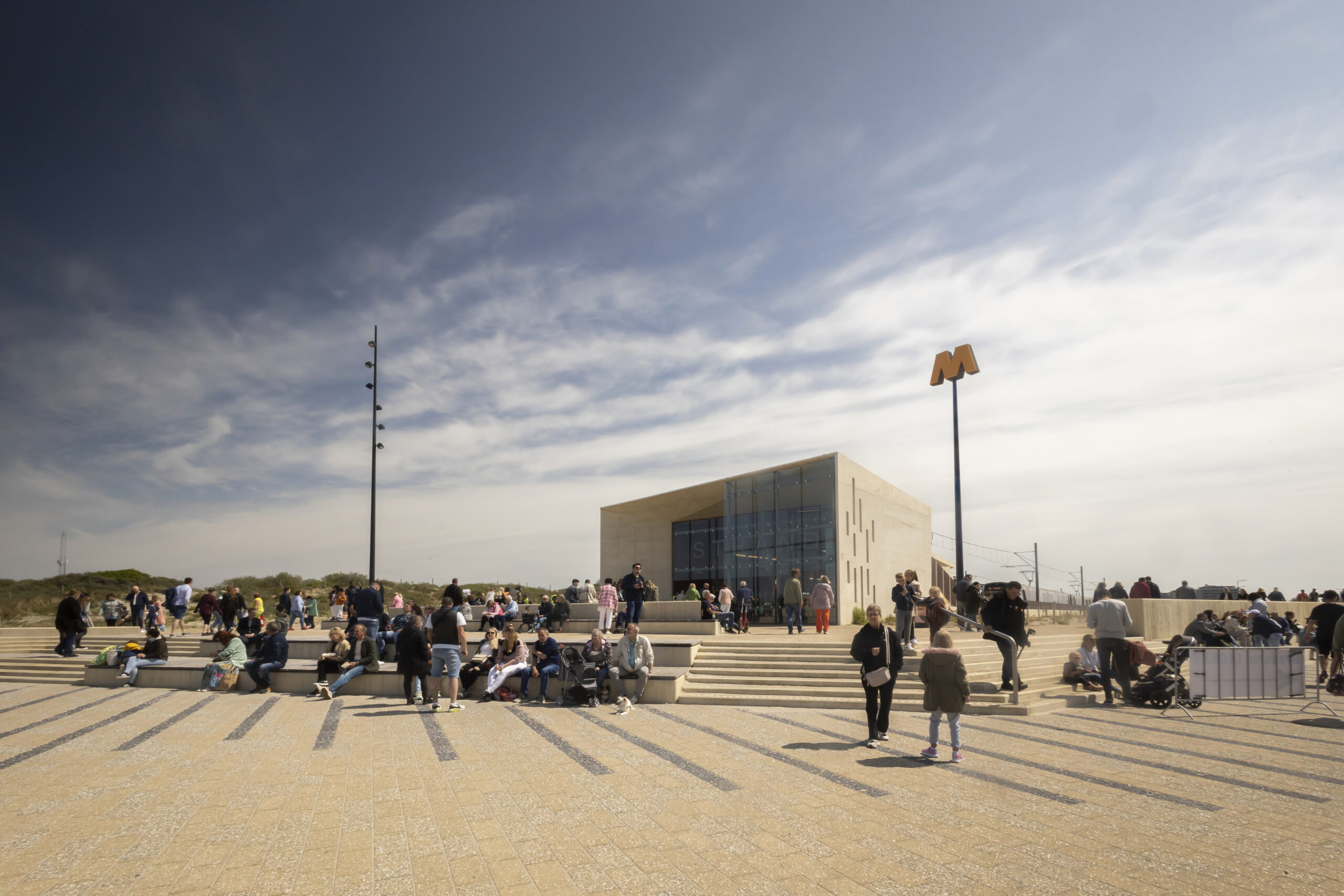 Toeristen genieten van de zon en van het uitzicht bij metrohalte Hoek van Holland Strand. Sinds 31 maart 2023 stopt metrolijn B op (eind)halte Hoek van Holland Strand. Hiermee reis je in 37 minuten tussen Rotterdam centrum en het strand, ook wel Rotterdam Beach genoemd.