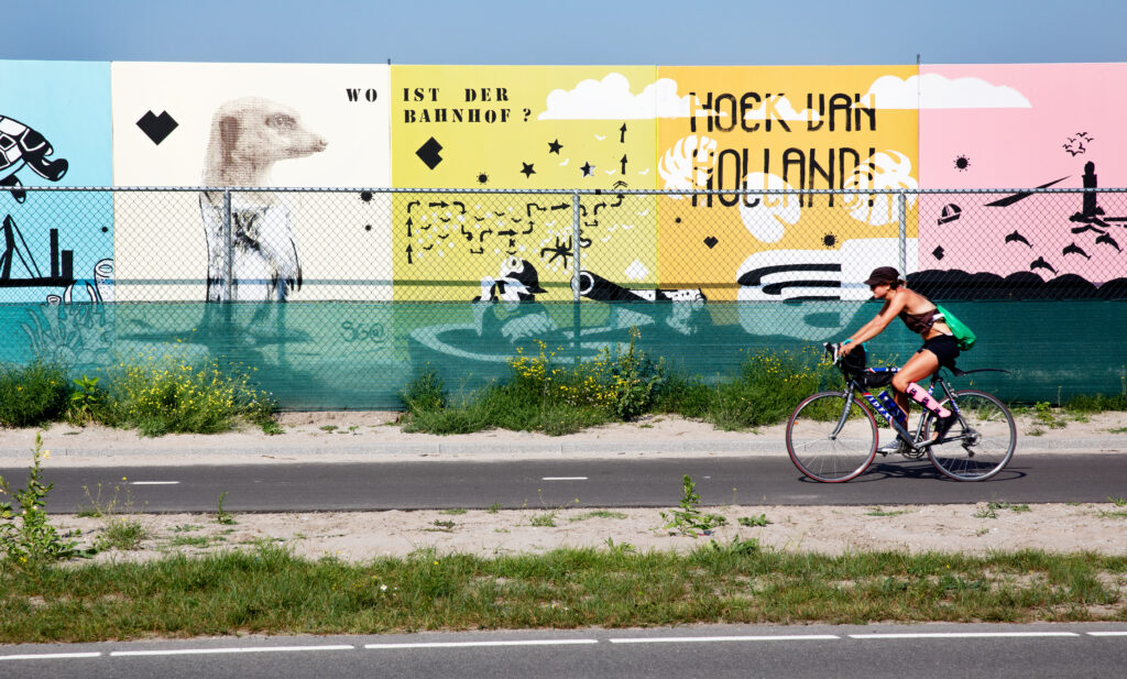Fietser opweg naar het strand in Hoek van Holland die langs vrolijke borden fietst.