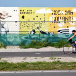Fietser opweg naar het strand in Hoek van Holland die langs vrolijke borden fietst.