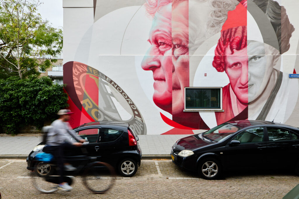 Fietser fietst langs Feyenoord streetart op een gevel in Rotterdam.