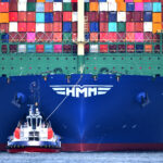 Schip met containers wordt door een sleeper de Rotterdamse haven in geloodst.