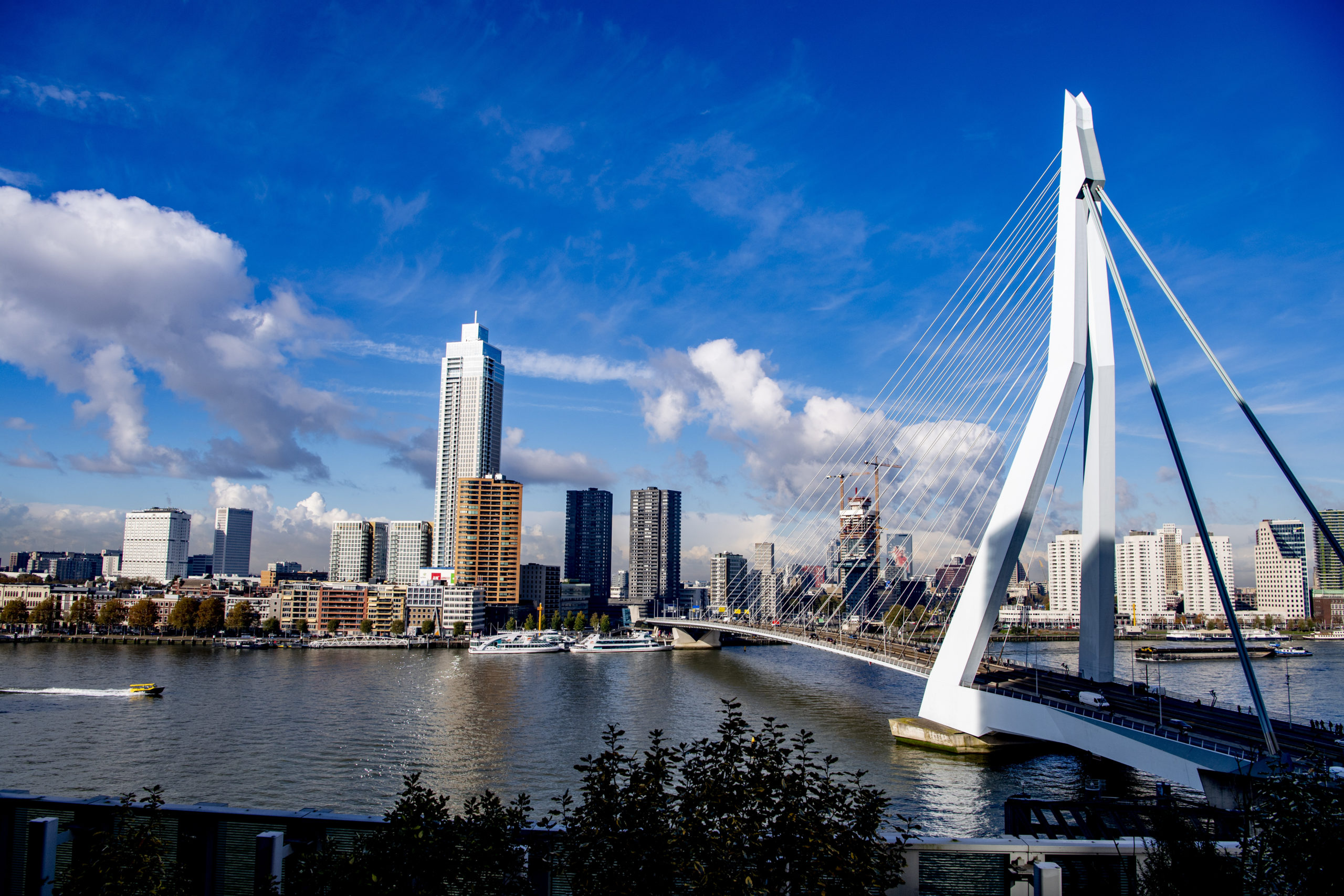 Zicht vanaf het nhow Rotterdam hotel op de Erasmusbrug met De Zalmhaven en de skyline van Rotterdam.