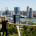 Mensen genieten van het uitzicht op de skyline en de Maas vanaf de Euromast